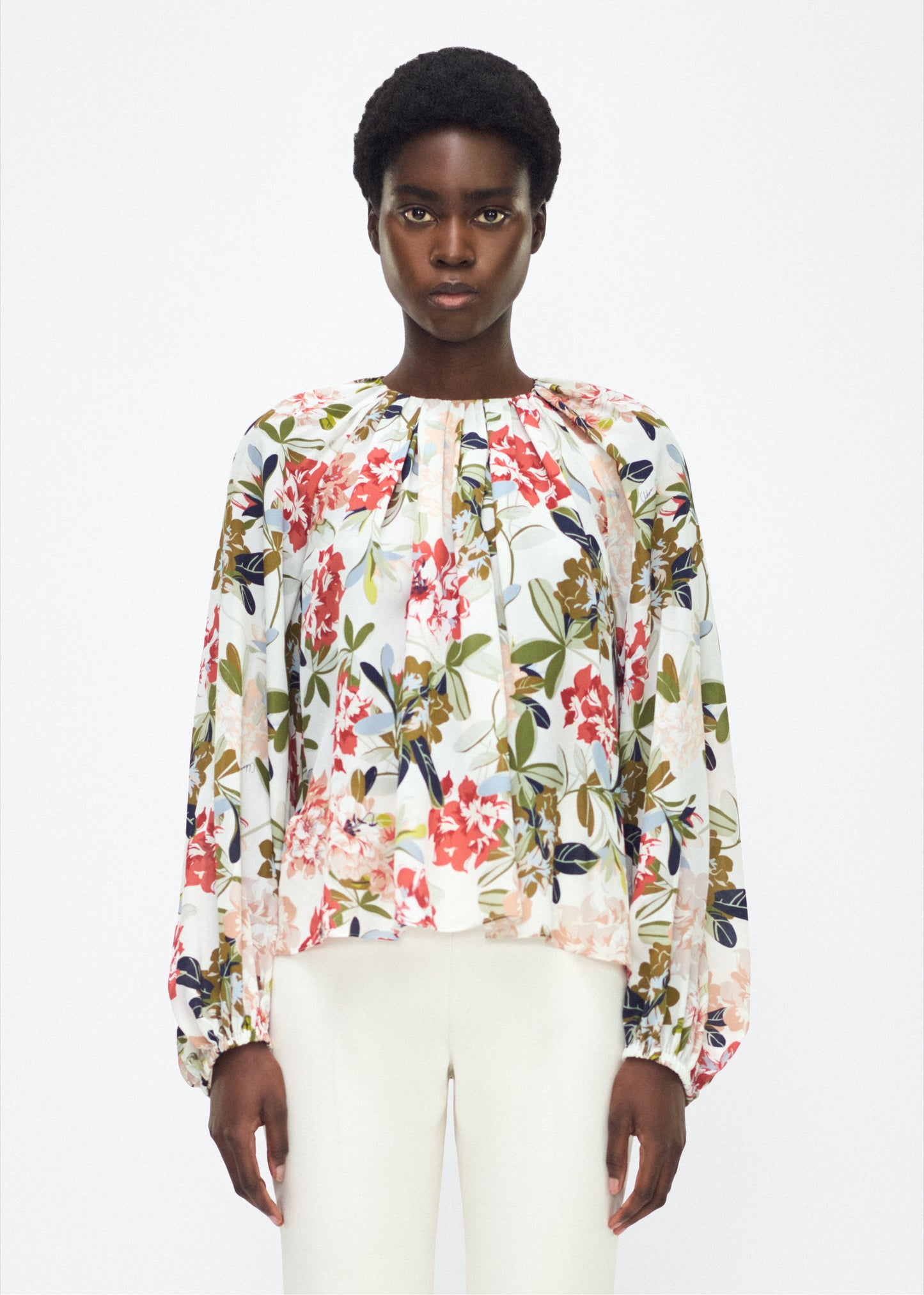 Model facing front – lottie top , P25130CC, ivory floral – Adam Lippes, P25 collection: The Lottie Top debuts in a new silhouette, featuring a classic ivory floral motif on refined crepe de chine. A delicately gathered neckline, airy sleeves, and soft hemline evoke a sense of lightness and fluidity.