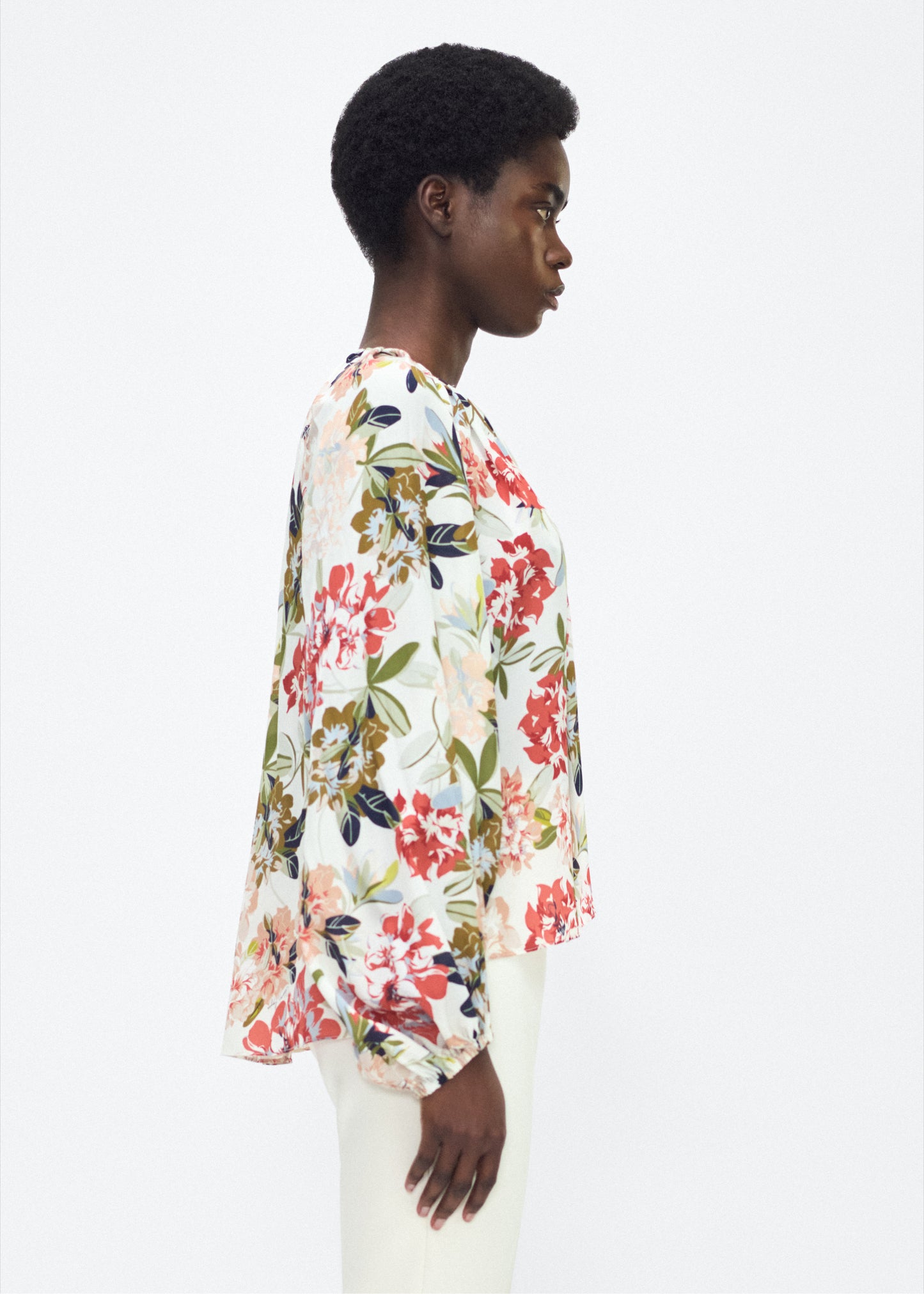 Model facing side – lottie top , P25130CC, ivory floral – Adam Lippes, P25 collection: The Lottie Top debuts in a new silhouette, featuring a classic ivory floral motif on refined crepe de chine. A delicately gathered neckline, airy sleeves, and soft hemline evoke a sense of lightness and fluidity.