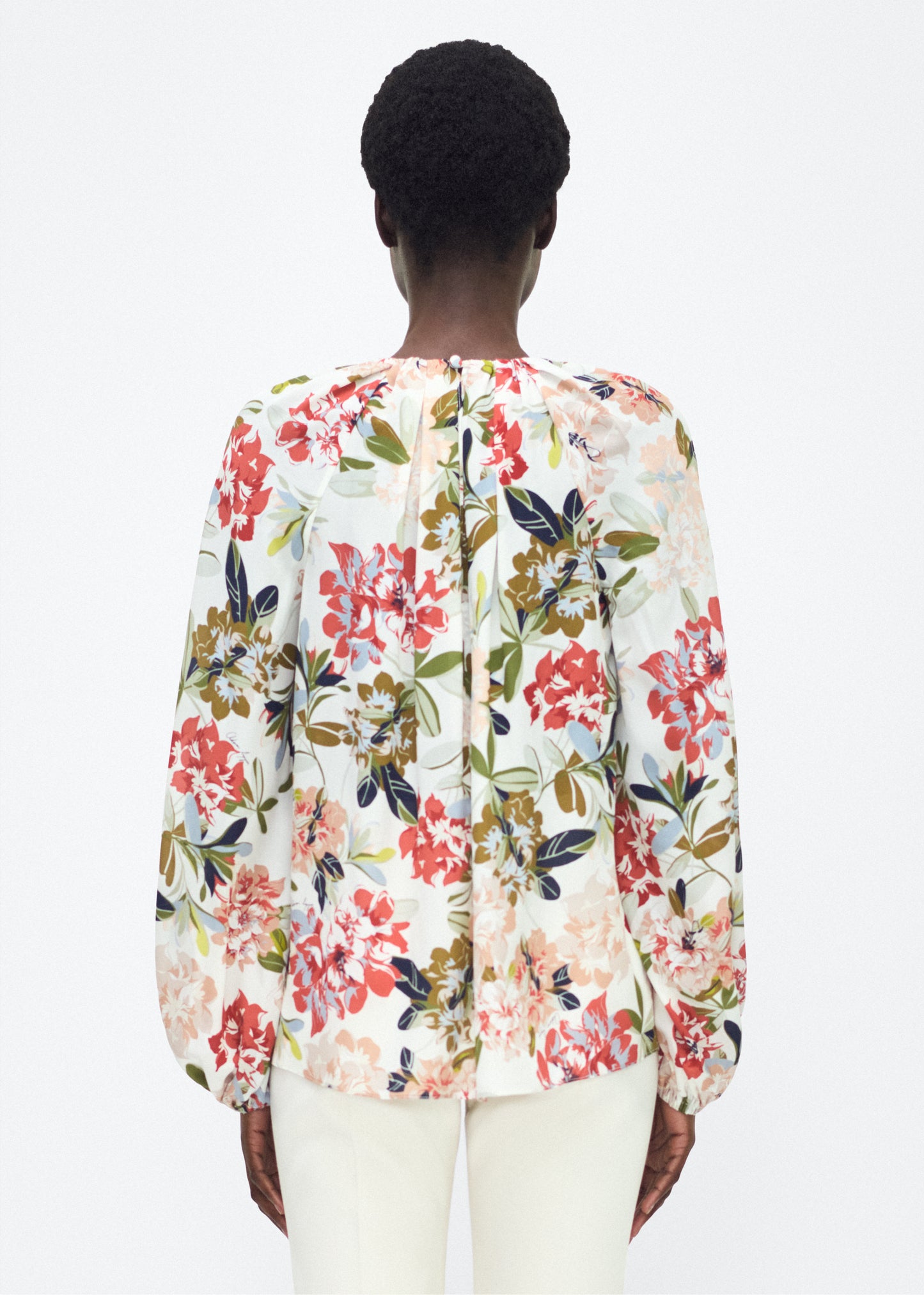 Model facing back – lottie top , P25130CC, ivory floral – Adam Lippes, P25 collection: The Lottie Top debuts in a new silhouette, featuring a classic ivory floral motif on refined crepe de chine. A delicately gathered neckline, airy sleeves, and soft hemline evoke a sense of lightness and fluidity.