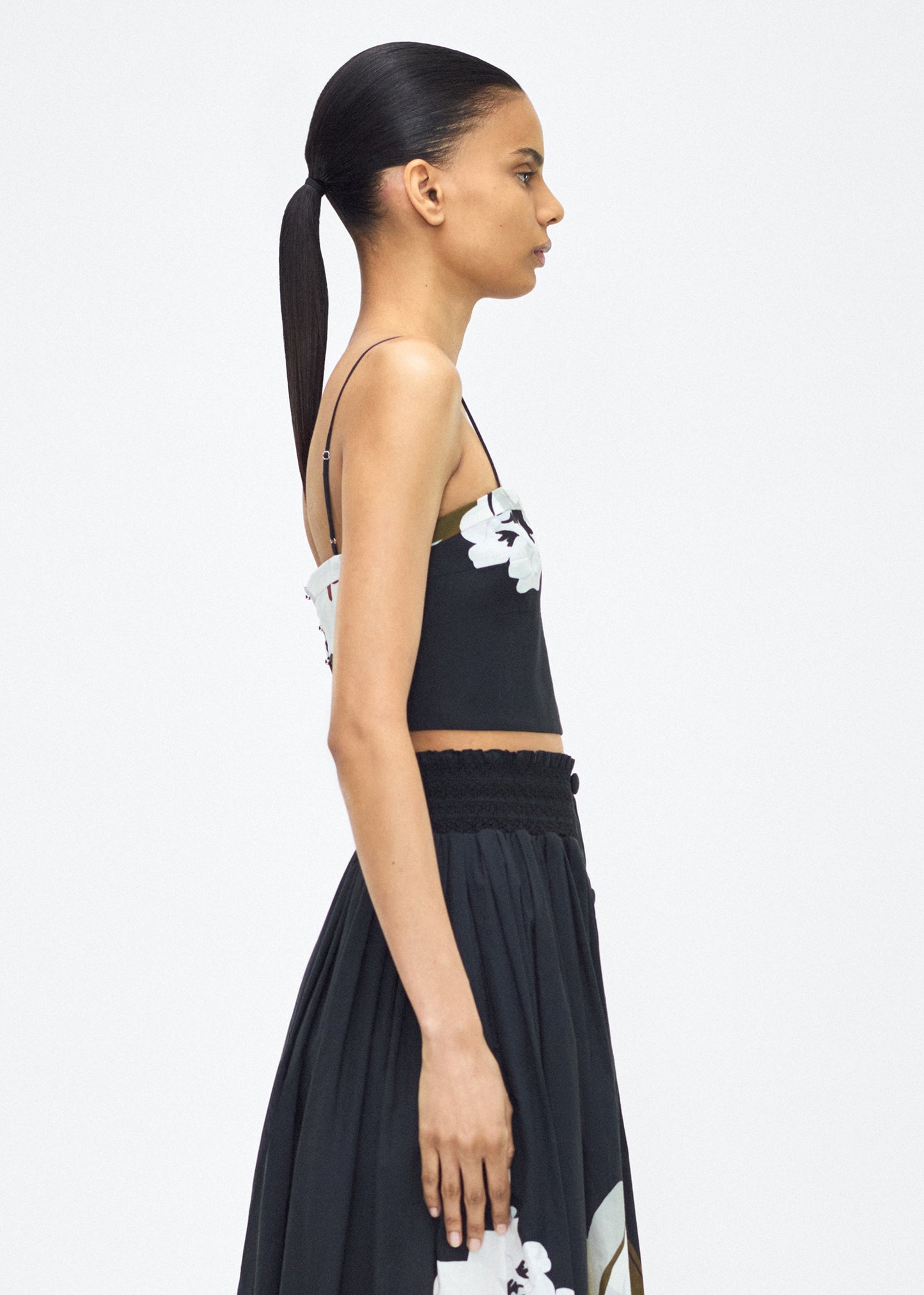 Model facing side wearing the bex top, P25143PV, black/white – Adam Lippes, P25 collection: Crafted from 100% cotton voile, the Bex Top showcases this season’s Sicily-inspired floral motif. The cropped silhouette offers a modern fit, while delicate straps and a clean neckline lend a minimalist touch.