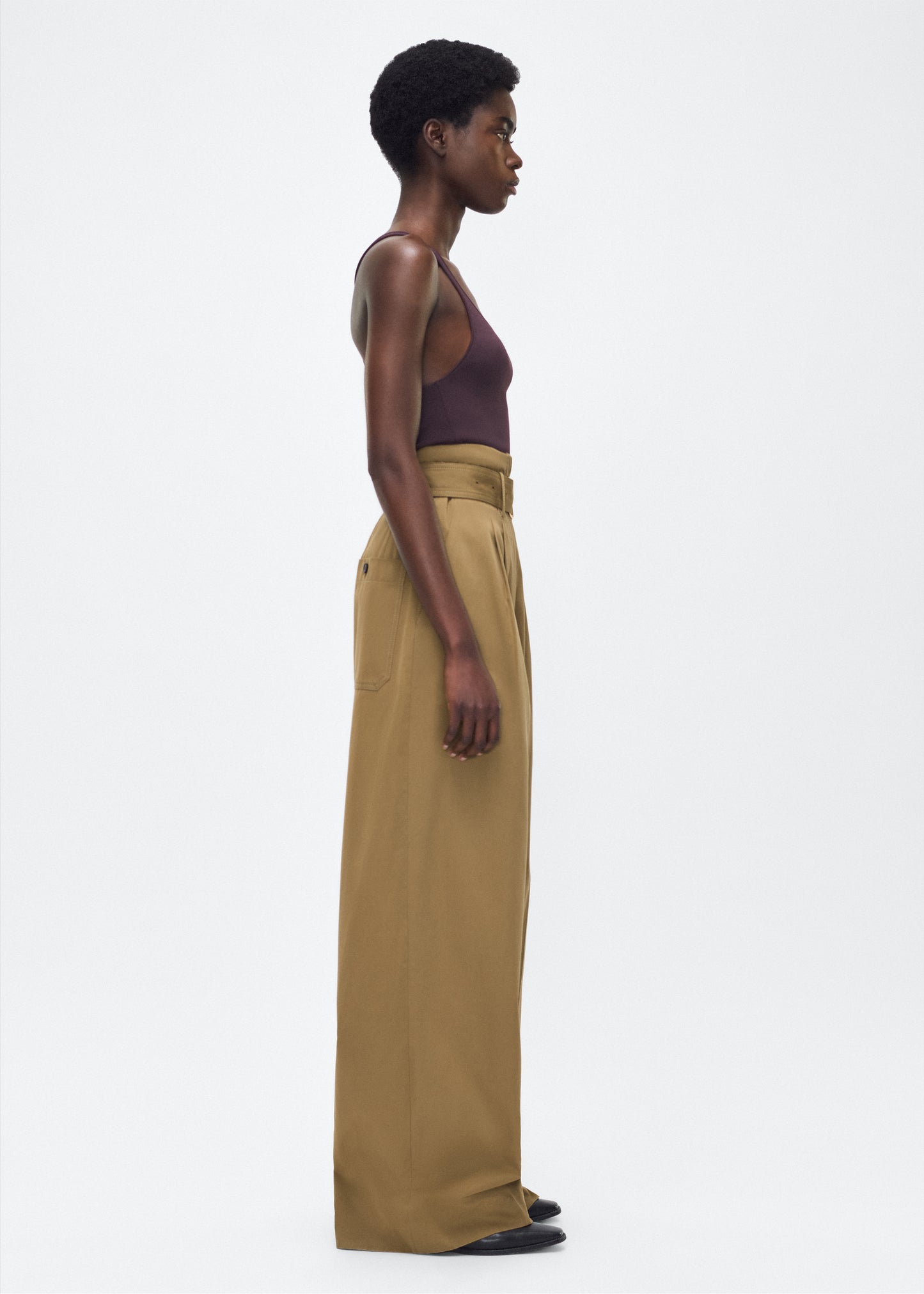Model facing side – Jericho Pant, P25505WI, Olive – Adam Lippes, P25 collection: The Jericho Pant is crafted from luxurious cotton-cashmere twill, offering the perfect balance of softness and structure. Pleated fronts and a wide-leg design create an easy, relaxed fit, while a belt at the waist adds elegant definition.