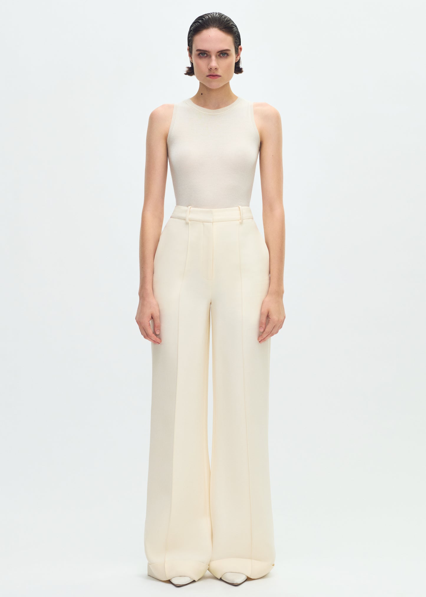 Image of a model facing forward wearing an ivory sleeveless tank tucked into ivory wide leg pants.