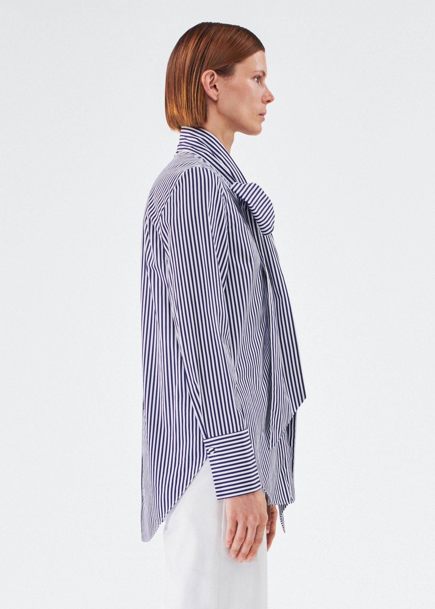 side view of model wearing lee blouse by adam lippes in striped poplin in navy and white