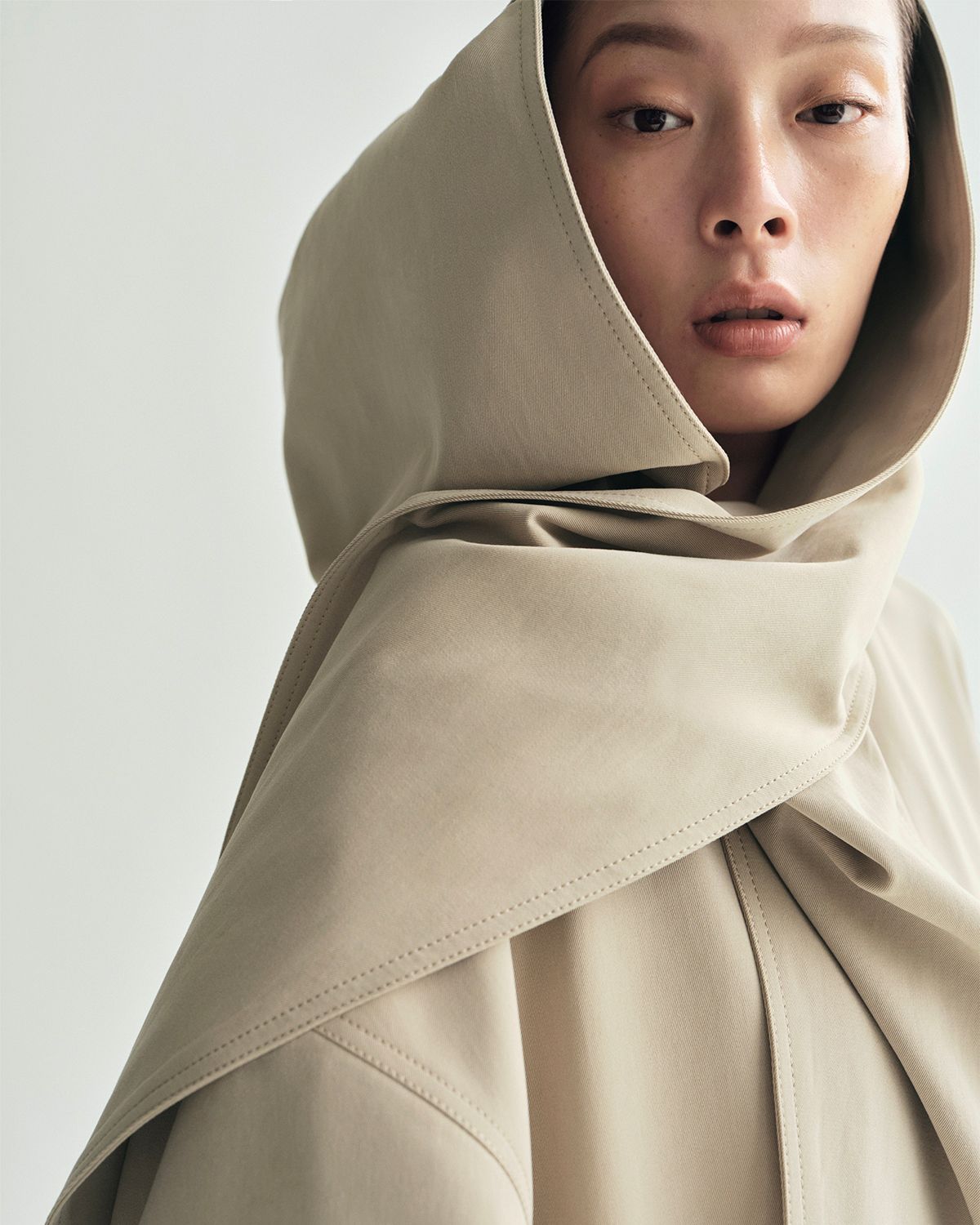 lookbook image of model wearing gesse coat in cotton twill in khaki with hood up 