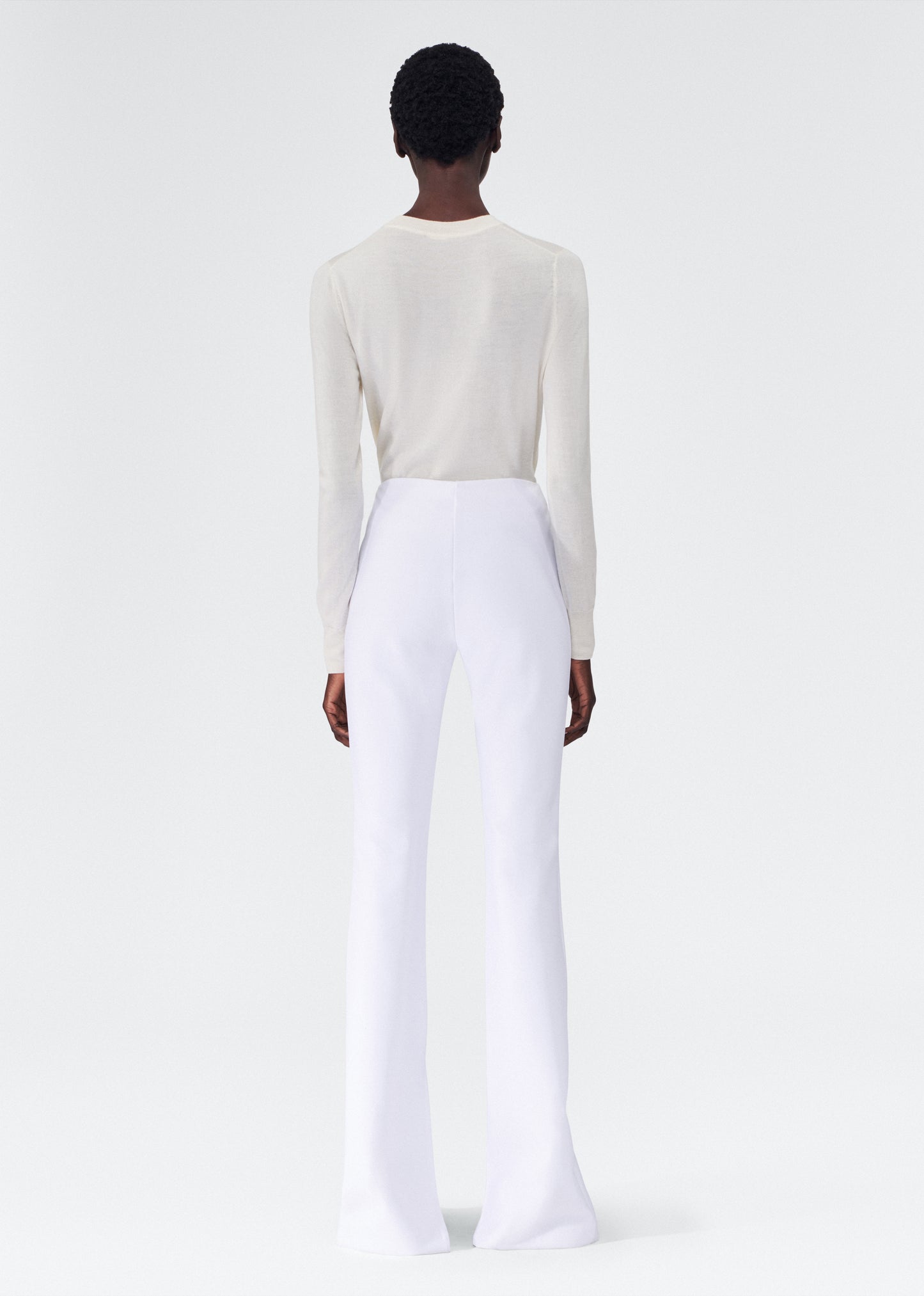back view of model wearing the adam lippes eva flare pant in bonded neoprene in white