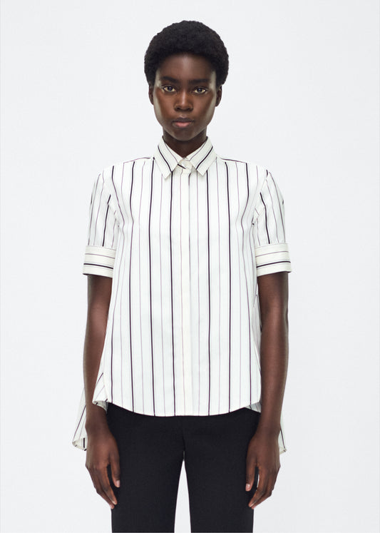 Model front facing image – Trapeze Shirt, P25106SS, Ivory/Black – Adam Lippes, P25 collection: The Adam Lippes Trapeze Shirt remains a timeless favorite from the atelier. Crafted from crisp Italian cotton, this season’s version features a classic ivory and black stripe. The piece features diamond monogram mother of pearl buttons along the center front placket, collar stand and French cuffs. Designed with side slits for a breezy, relaxed fit.