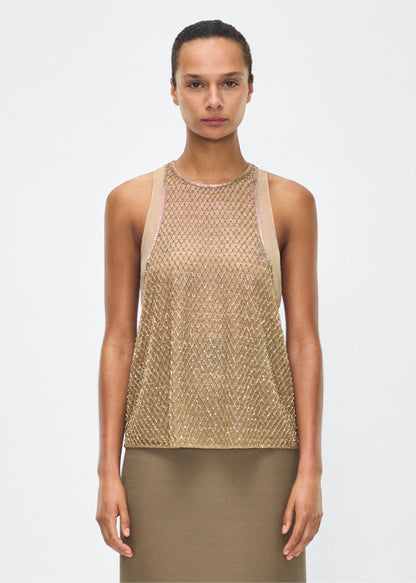 Image of model facing front – Fable Top, P25110TU, Gold – Adam Lippes, P25 collection: The Fable Top in beaded tulle features intricate glass beading, a meticulous hand-done process that takes several days, arranged in the signature diamond motif for a striking visual effect. This new shape from the atelier combines fine craftsmanship with a clean, modern silhouette.