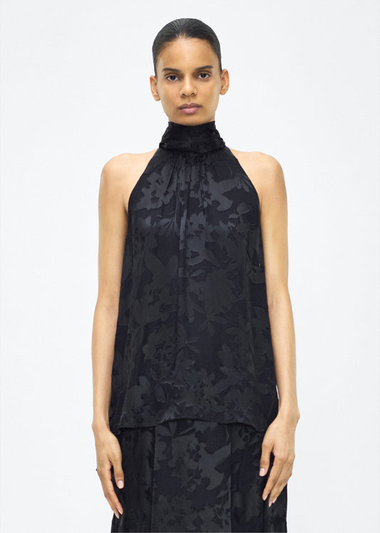 Image of model facing front – giulia top, P25117DV, Black – Adam Lippes, P25 collection: The Giulia Top is crafted from elegant burn-out fabric, and features an intricate floral design. The classic black hue enhances the rich texture, while the flowing silhouette exudes sophistication. Pair with the Emi Skirt in Devore for a coordinated ensemble.