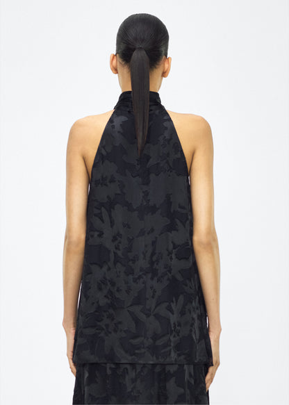 Image of model facing back – giulia top, P25117DV, Black – Adam Lippes, P25 collection: The Giulia Top is crafted from elegant burn-out fabric, and features an intricate floral design. The classic black hue enhances the rich texture, while the flowing silhouette exudes sophistication. Pair with the Emi Skirt in Devore for a coordinated ensemble.