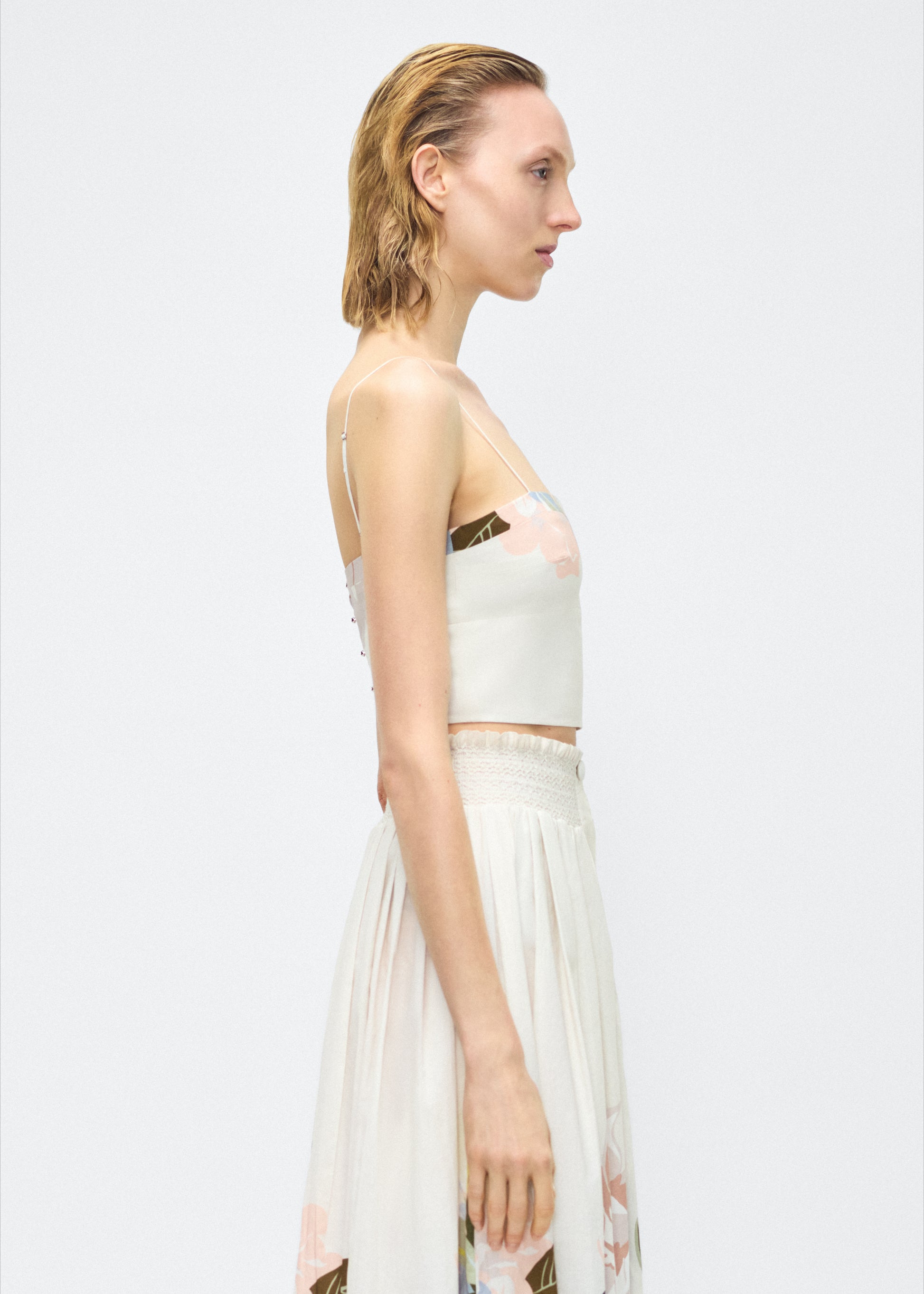 Image of model facing side – bex top, P25143PV, champagne/multi – Adam Lippes, P25 collection: Crafted from 100% cotton voile, the Bex Top showcases this season’s Sicily-inspired floral motif. The cropped silhouette offers a modern fit, while delicate straps and a clean neckline lend a minimalist touch. 