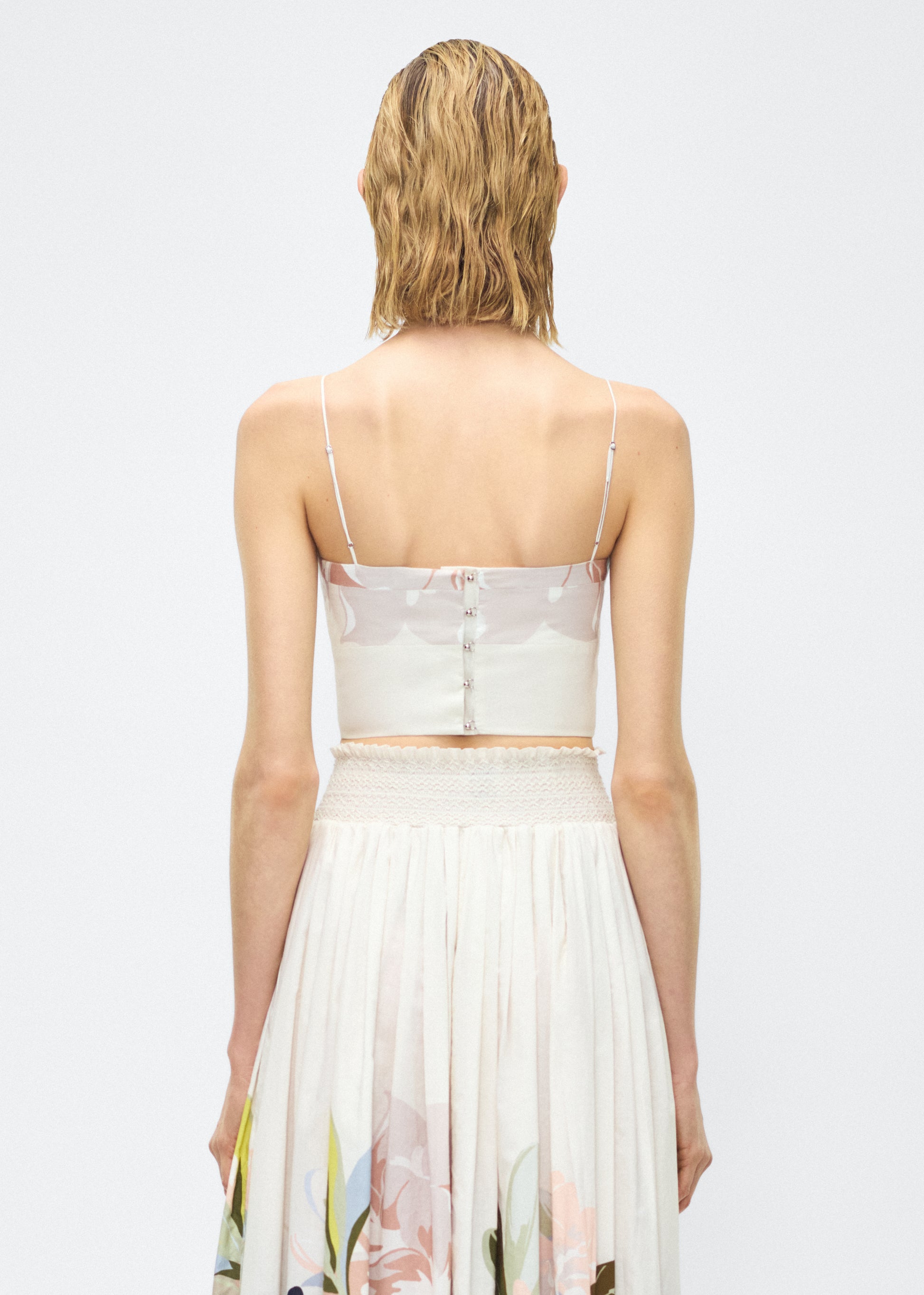 Image of model facing back – bex top, P25143PV, champagne/multi – Adam Lippes, P25 collection: Crafted from 100% cotton voile, the Bex Top showcases this season’s Sicily-inspired floral motif. The cropped silhouette offers a modern fit, while delicate straps and a clean neckline lend a minimalist touch. 