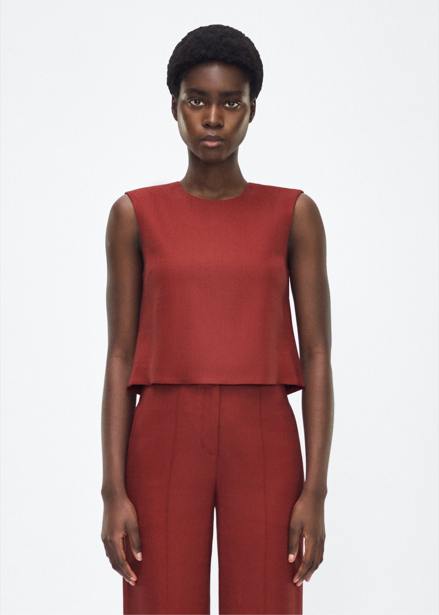 Image of model facing front– mercer top, P25144TR, sienna – Adam Lippes, P25 collection: This cropped-silhouette top is crafted from stretch canvas in a rich sienna hue, offering a perfect balance of softness and structure. A box pleat at the back adds subtle, refined shape.