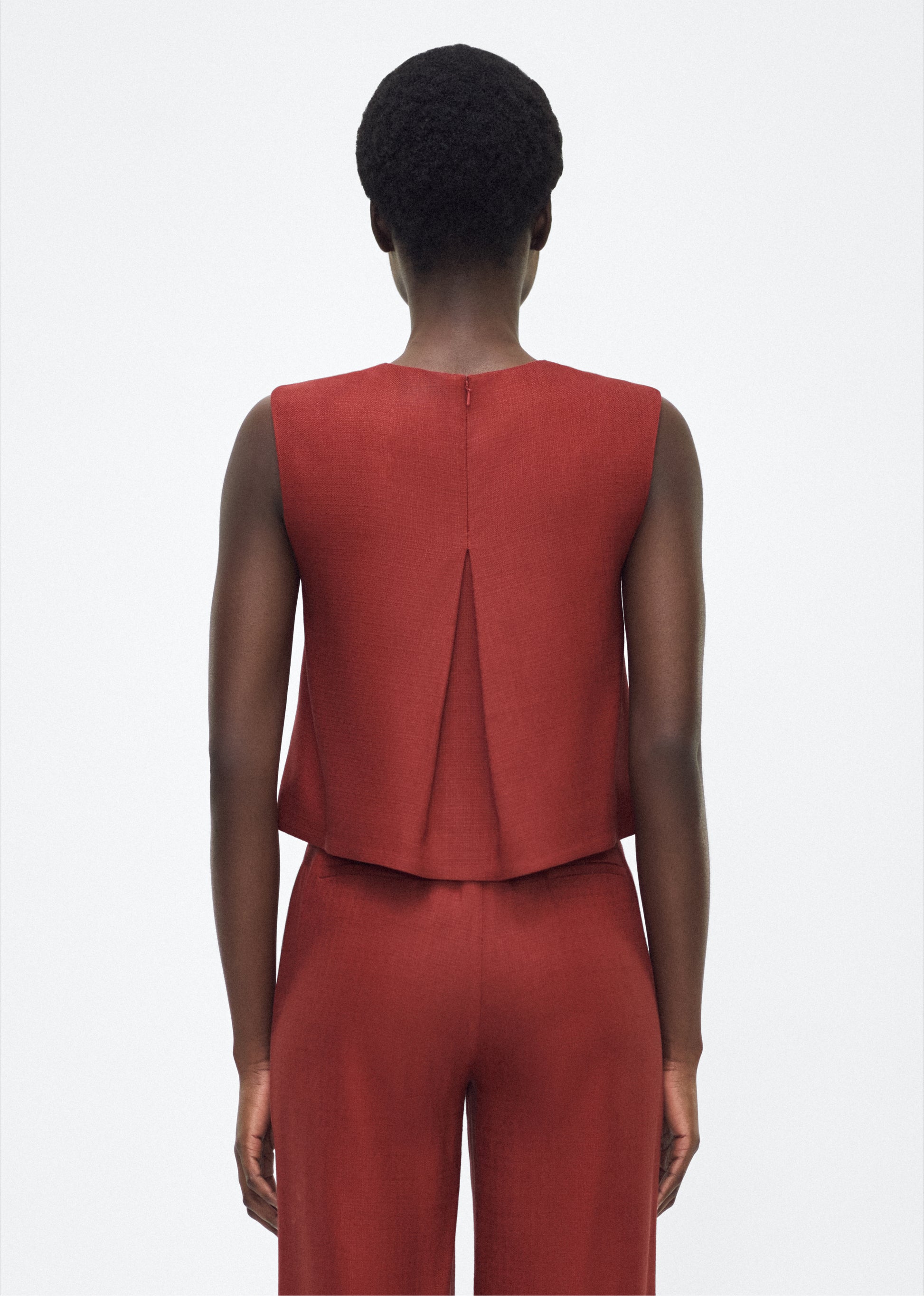 Image of model facing back  mercer top, P25144TR, sienna – Adam Lippes, P25 collection: This cropped-silhouette top is crafted from stretch canvas in a rich sienna hue, offering a perfect balance of softness and structure. A box pleat at the back adds subtle, refined shape.
