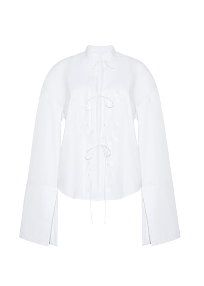 ghost image front – mick top, P25145CS, white – Adam Lippes, P25 collection: A new shape for the season, the Mick Top is crafted from crisp organic cotton poplin in classic white. The top features a tie closure at the center front, adding a subtle touch of modern sophistication. Billowy sleeves with split cuffs create an airy and elegant silhouette. Includes a silk cami for added comfort and versatility.
