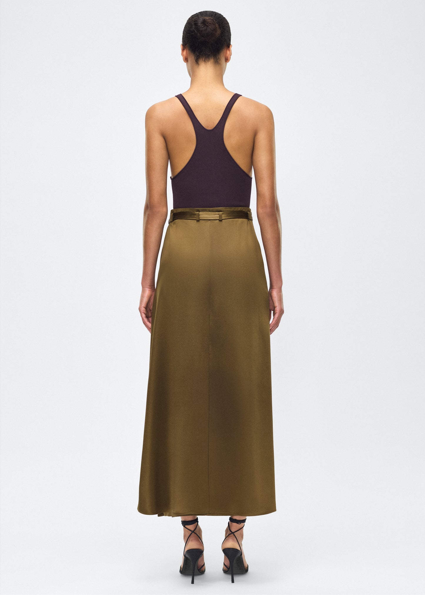 model image back - bruna skirt, P25403HM, olive – Adam Lippes, P25 collection: The Bruna Skirt is crafted from luxurious double-face silk charmeuse, offering a rich sheen and fluid drape. Rendered in a deep olive hue, cascading fabric at the side of the piece adds subtle movement to the elegant silhouette. 