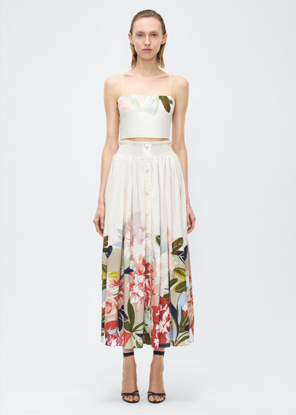 Image of model front– Lovisa Skirt, P25418PV, Champagne Multi – Adam Lippes, P25 collection: A signature shape from the atelier, the Lovisa Skirt is crafted from airy printed voile featuring a vibrant Sicily-inspired floral motif. Designed with a smocked waistband for a comfortable fit, the skirt is finished with fabric-covered buttons down the center front. Pair with the Bex Top in Printed Voile for a coordinated look.
