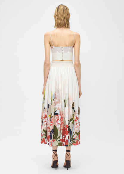Image of model back- Lovisa Skirt, P25418PV, Champagne Multi – Adam Lippes, P25 collection: A signature shape from the atelier, the Lovisa Skirt is crafted from airy printed voile featuring a vibrant Sicily-inspired floral motif. Designed with a smocked waistband for a comfortable fit, the skirt is finished with fabric-covered buttons down the center front. Pair with the Bex Top in Printed Voile for a coordinated look.