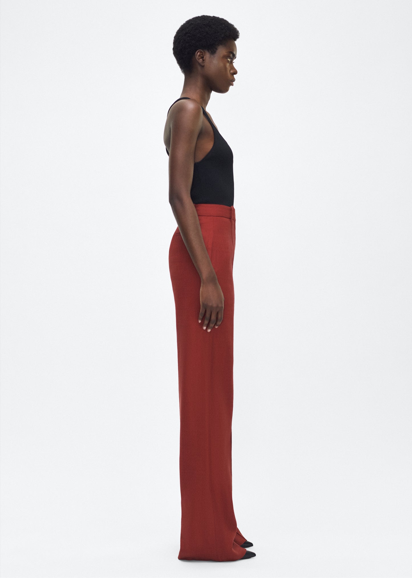 Image of model facing side – Wyatt Pant, P25507TR, Sienna – Adam Lippes, P25 collection: Precision tailoring meets modern ease in the Wyatt Pant, crafted in lightweight canvas and rendered in a rich sienna hue. The silhouette is clean and elongating, with a high-rise waist and fabric that moves effortlessly while holding its shape.