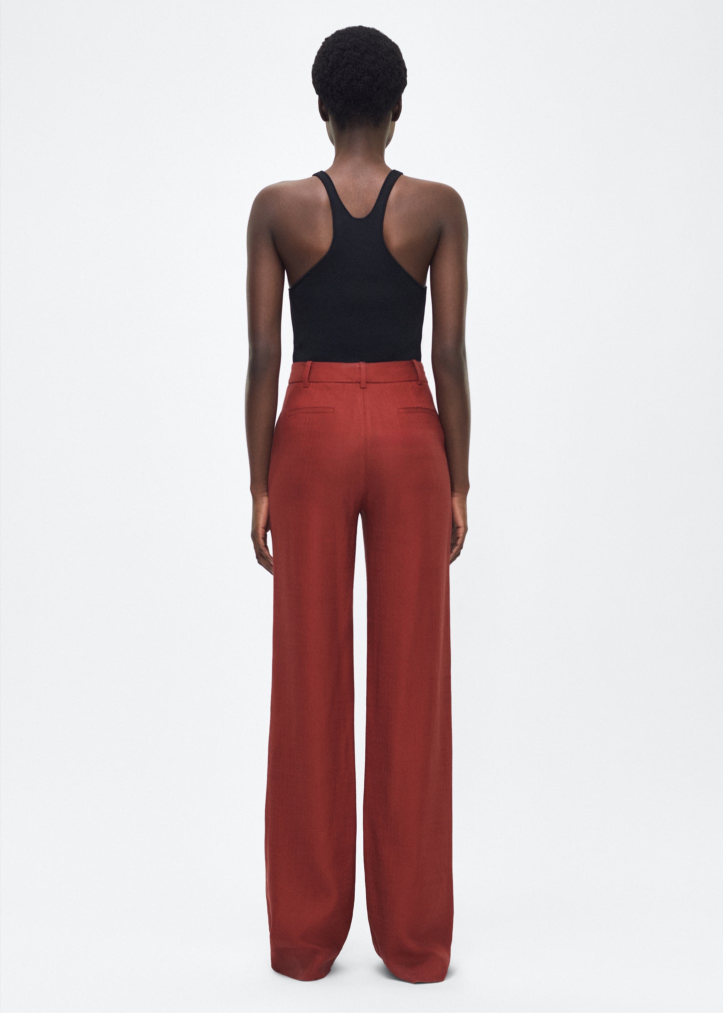 Image of model facing back – Wyatt Pant, P25507TR, Sienna – Adam Lippes, P25 collection: Precision tailoring meets modern ease in the Wyatt Pant, crafted in lightweight canvas and rendered in a rich sienna hue. The silhouette is clean and elongating, with a high-rise waist and fabric that moves effortlessly while holding its shape.
