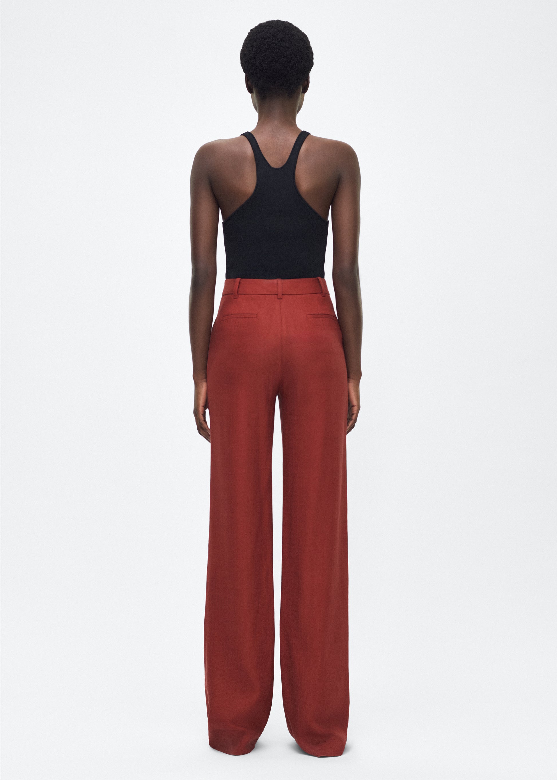 Image of model facing back – Wyatt Pant, P25507TR, Sienna – Adam Lippes, P25 collection: Precision tailoring meets modern ease in the Wyatt Pant, crafted in lightweight canvas and rendered in a rich sienna hue. The silhouette is clean and elongating, with a high-rise waist and fabric that moves effortlessly while holding its shape.
