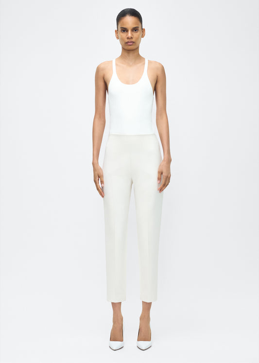 Model facing forward wearing – Kit Pant, P25512VT, Ivory – Adam Lippes, P25 collection: The Kit Pant introduces a sleek new silhouette, impeccably tailored in compact viscose. Designed to contour the legs, this ankle-grazing pant delivers effortless polish and modern ease.