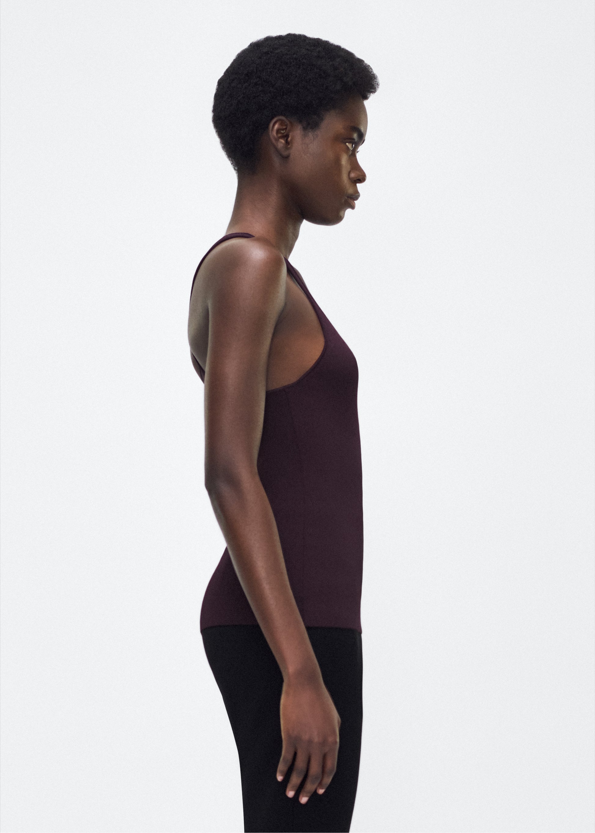 Image of model facing side – lumii tank , P25601VI, cacao – Adam Lippes, P25 collection: A new silhouette from the atelier, the Lumii Tank is crafted from luxurious knitted viscose. Clean lines and athletic-inspired straps make it a versatile piece for layering or wearing alone.