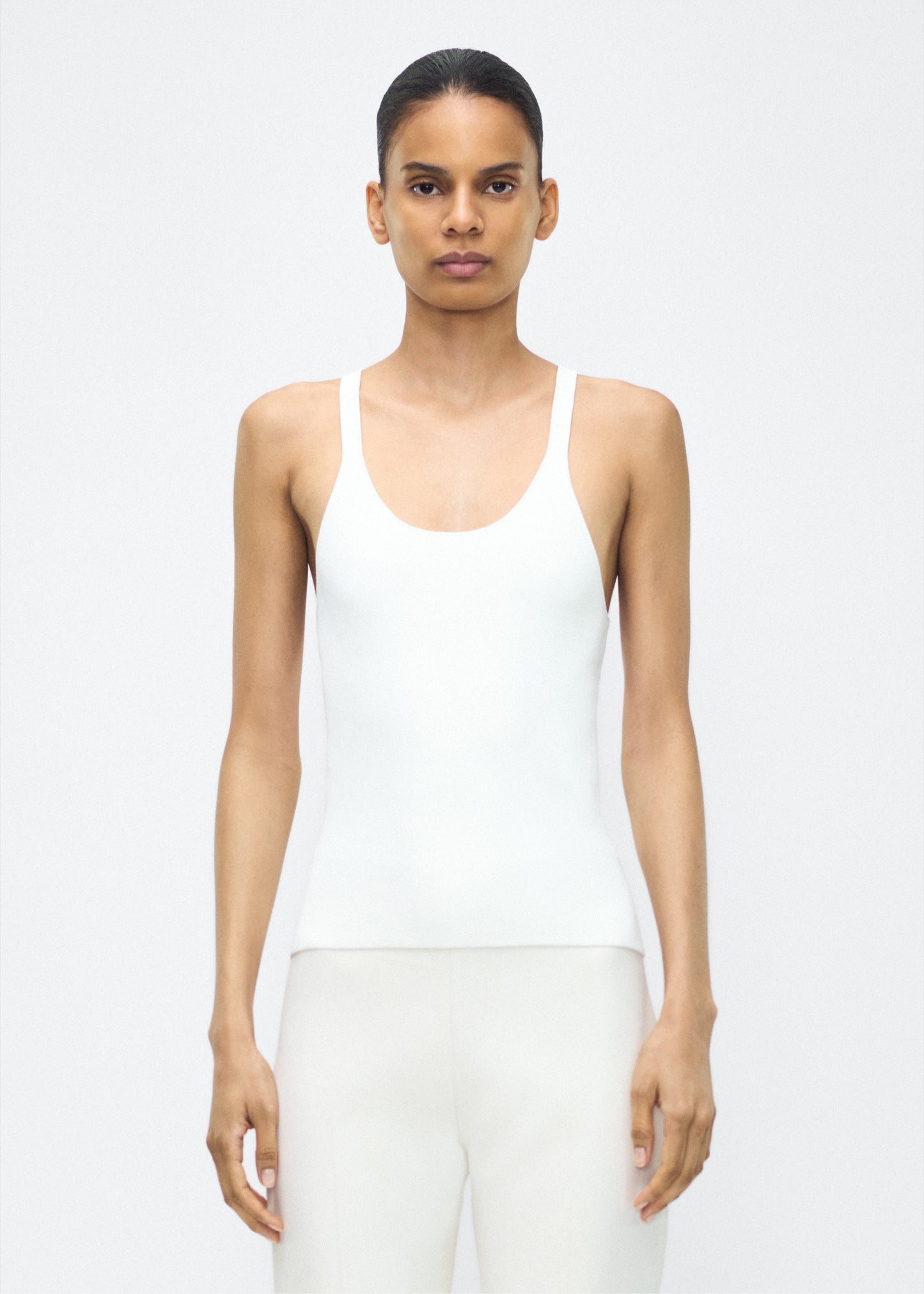 Image of model facing the front– lumii tank , P25601VI, ivory – Adam Lippes, P25 collection:A new silhouette from the atelier, the Lumii Tank is crafted from luxurious knitted viscose. Clean lines and athletic-inspired straps make it a versatile piece for layering or wearing alone.