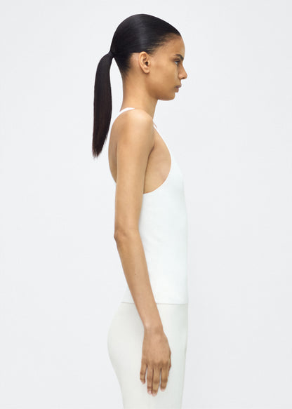 Image of model facing the side lumii tank , P25601VI, ivory – Adam Lippes, P25 collection:A new silhouette from the atelier, the Lumii Tank is crafted from luxurious knitted viscose. Clean lines and athletic-inspired straps make it a versatile piece for layering or wearing alone.