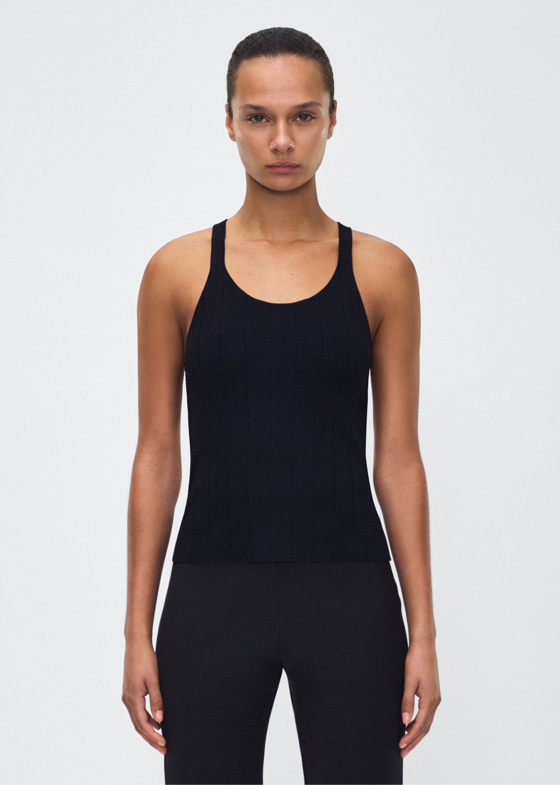 Image of model facing front– lumii tank , P25624UB, black – Adam Lippes, P25 collection: A new silhouette from the atelier, the Lumii Tank is crafted from structured compact jacquard. Clean lines and athletic-inspired straps make it a versatile piece for layering or wearing alone.
