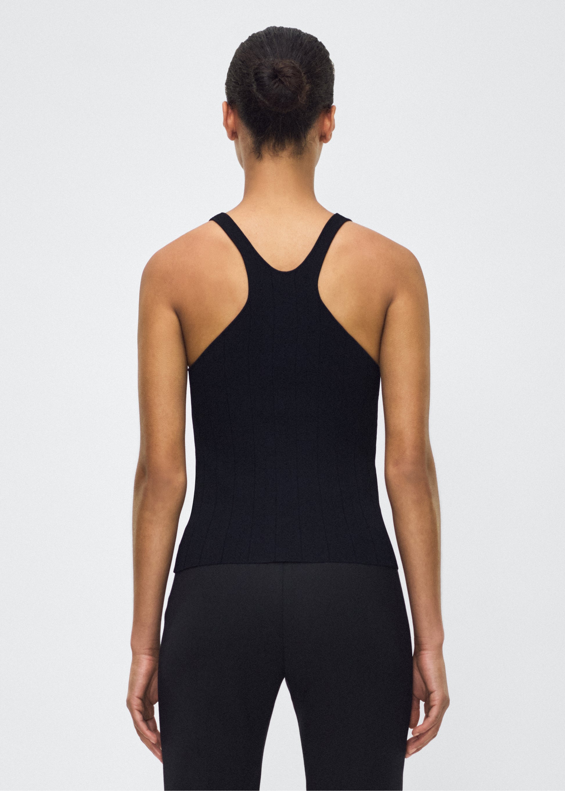 Image of model facing back with  lumii tank , P25624UB, black – Adam Lippes, P25 collection: A new silhouette from the atelier, the Lumii Tank is crafted from structured compact jacquard. Clean lines and athletic-inspired straps make it a versatile piece for layering or wearing alone.