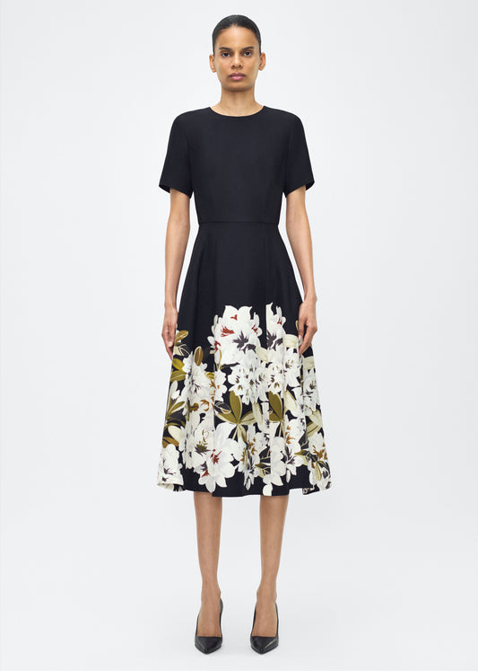 Model facing front, wearing P25722PW, the Evangeline Dress in Black/white; From the Adam Lippes P25 Collection, A signature silhouette from the atelier, the Evangeline Dress is crafted in luxurious printed silk wool adorned with this season’s Sicily-inspired floral motif. Designed with an A-line silhouette and a gently flared skirt, it drapes gracefully for an elegant look.