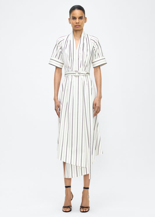Model facing front, P25723SS, Ivory/Black, P25 Adam Lippes collection: The Nansi Dress is crafted from crisp stripe poplin in ivory and black, featuring an asymmetrical hem that adds a modern twist to a classic design. A sleek V-neckline and short sleeves enhance its effortless sophistication, while a fabric belt cinches the waist for a defined silhouette.