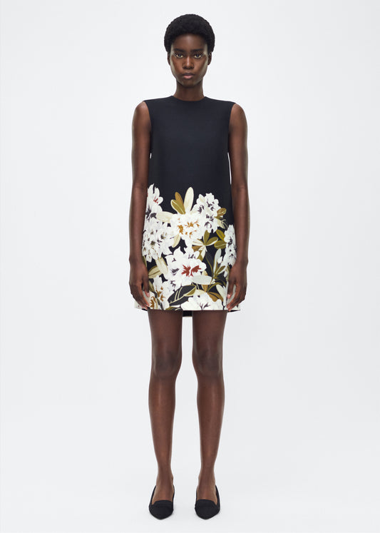 Model facing forward, P25750PW, Adam Lippes P25 Collection, The Ani Dress. Rendered in luxurious silk wool, the Ani Dress features this season’s Sicily-inspired floral motif. The dress is designed with a clean, sleeveless silhouette, offering a sharp A-line shape that gracefully skims the body. 