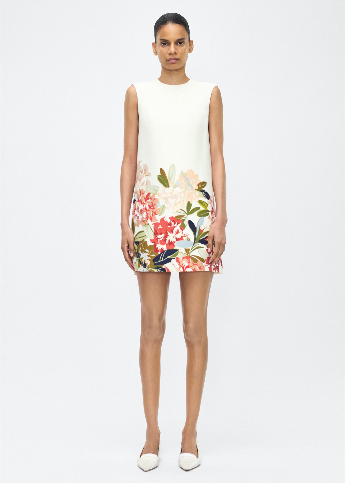 image of model facing front – ani dress, P25750PW, ivory multi – Adam Lippes, P25 collection: Rendered in luxurious silk wool, the Ani Dress features this season’s Sicily-inspired floral motif. The dress is designed with a clean, sleeveless silhouette, offering a sharp A-line shape that gracefully skims the body. 
