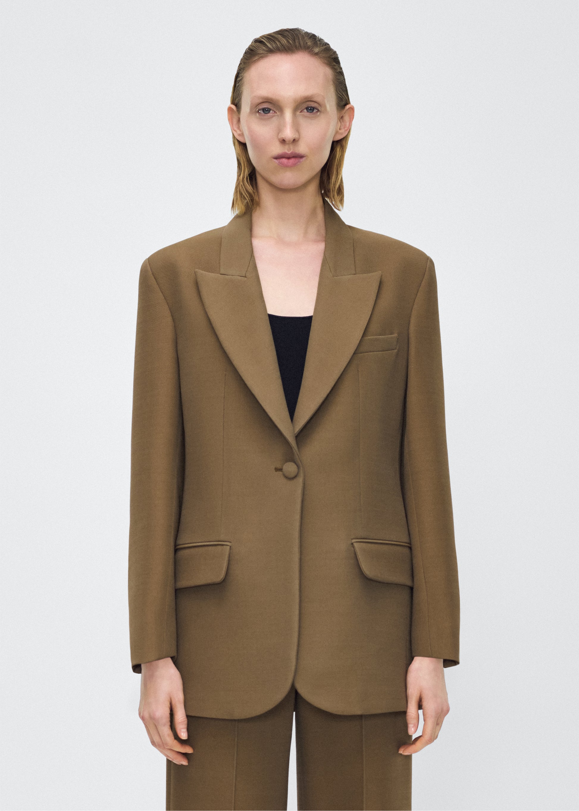Model facing front, wearing the brody jacket in military green color, Adam Lippes P25 collection, A signature shape from the atelier, the Brody Jacket is crafted from luxurious silk wool, offering a soft yet structured silhouette. Designed with a single button closure, front pockets, and a sleek notched collar, this jacket effortlessly elevates any ensemble.