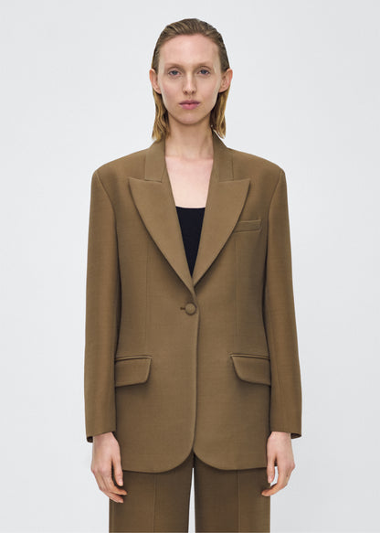 Model facing front, wearing the brody jacket in military green color, Adam Lippes P25 collection, A signature shape from the atelier, the Brody Jacket is crafted from luxurious silk wool, offering a soft yet structured silhouette. Designed with a single button closure, front pockets, and a sleek notched collar, this jacket effortlessly elevates any ensemble.