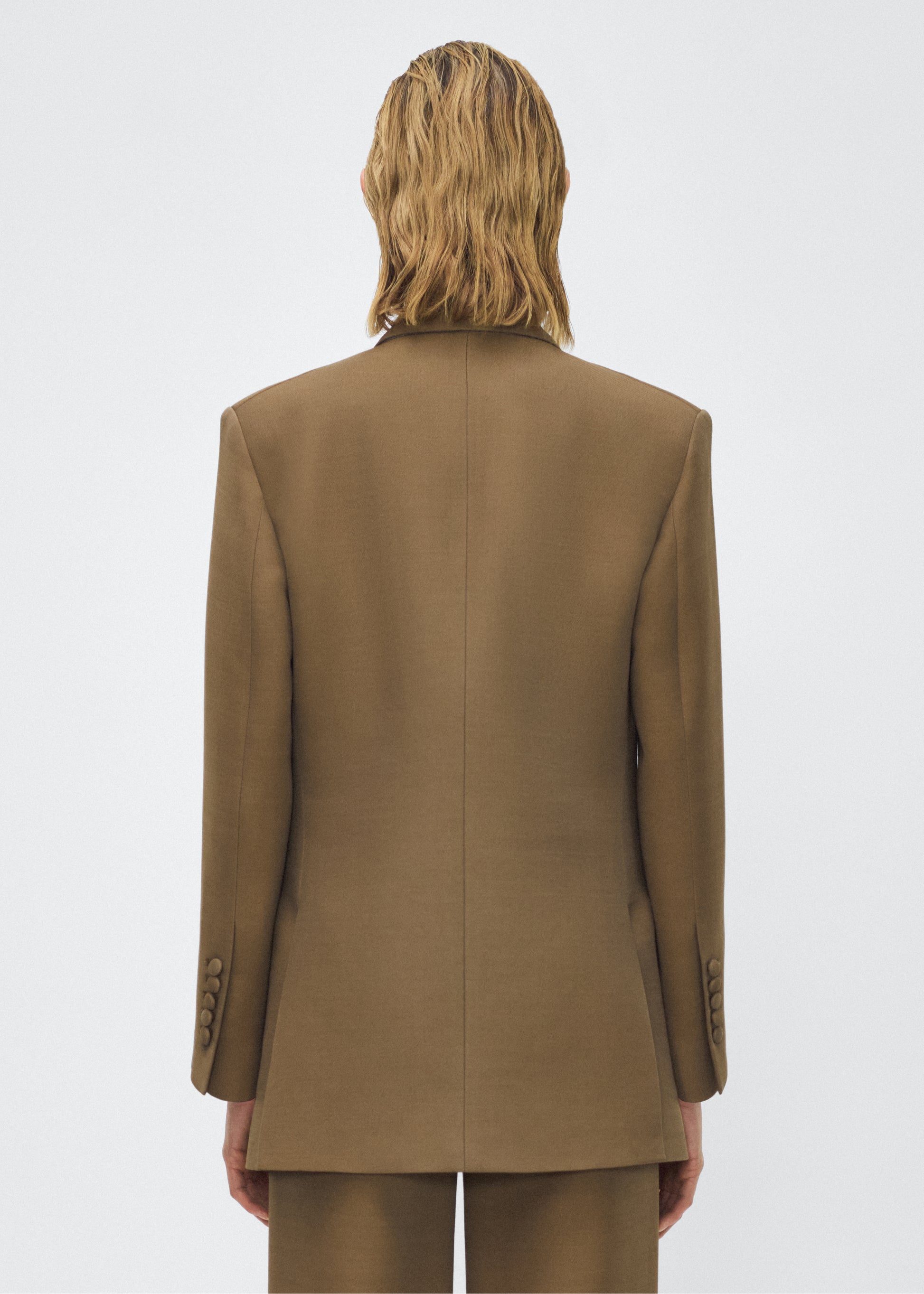 Model facing back, wearing the brody jacket in military green color, Adam Lippes P25 collection, A signature shape from the atelier, the Brody Jacket is crafted from luxurious silk wool, offering a soft yet structured silhouette. Designed with a single button closure, front pockets, and a sleek notched collar, this jacket effortlessly elevates any ensemble.