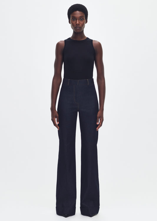 Forward facing model wearing a black sleeveless tank tuked into a dark denim jean. 