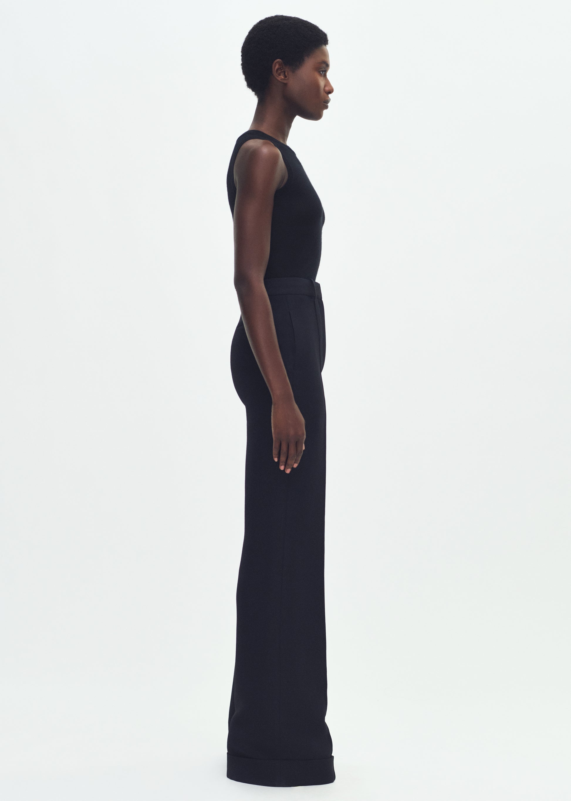 Image of a model facing forward wearing a black sleeveless top tucked into black wide leg pants.
