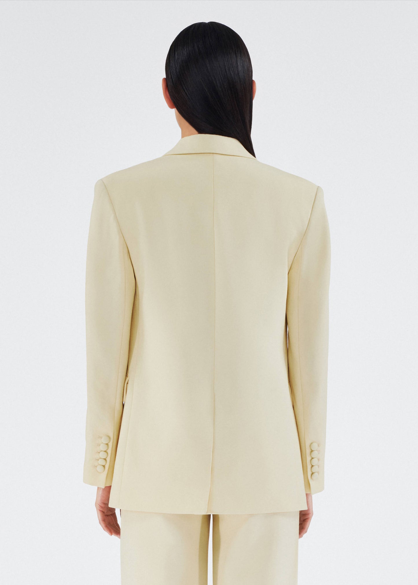 back view of model wearing a classic adam lippes blazer in silk wool rendered in a beurre hue