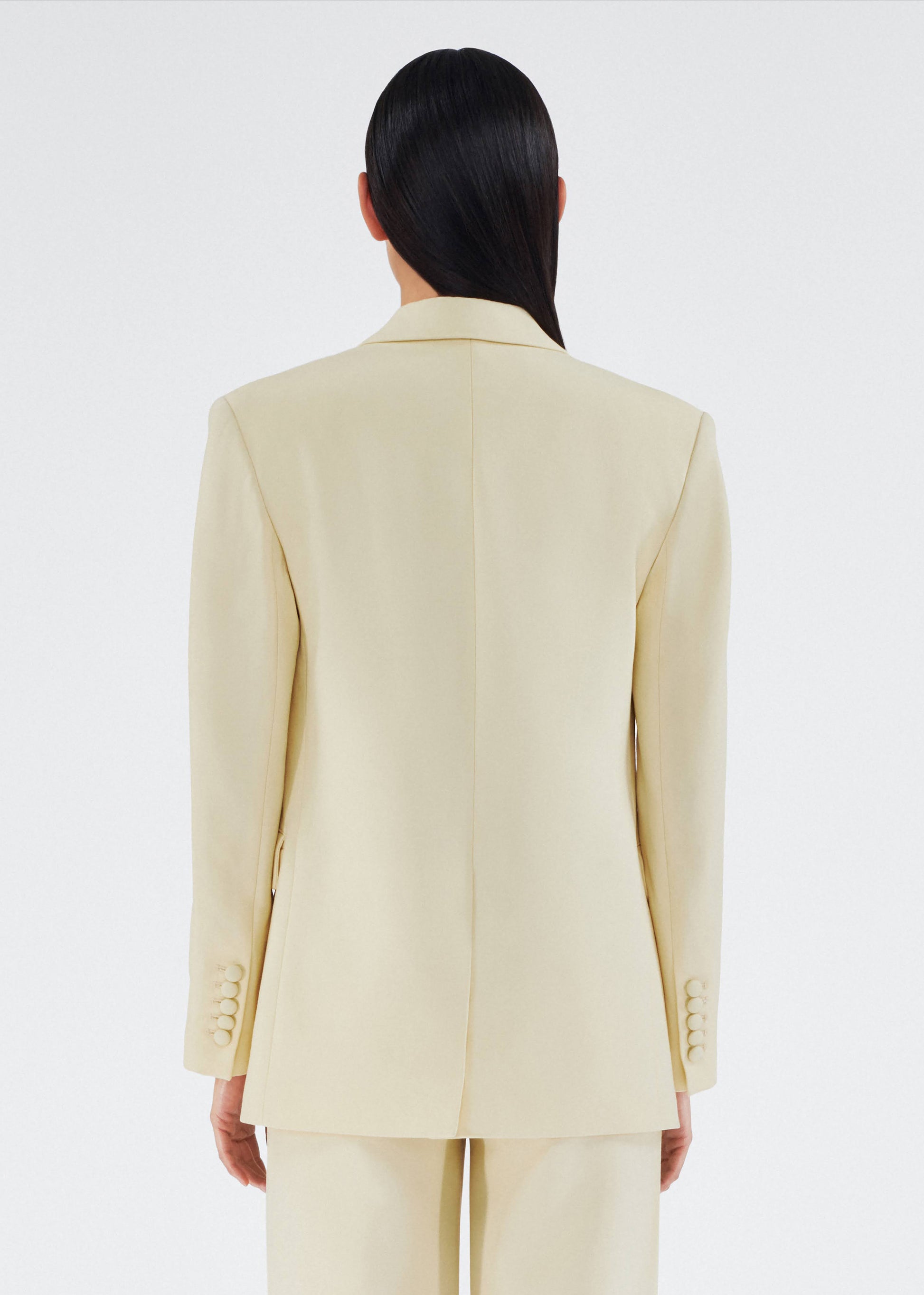 back view of model wearing a classic adam lippes blazer in silk wool rendered in a beurre hue