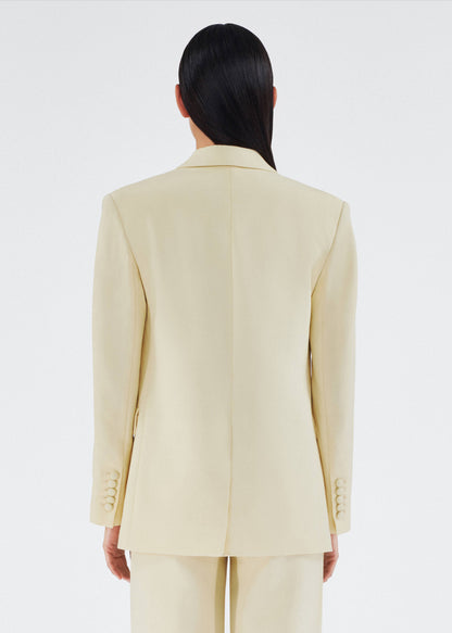 back view of model wearing a classic adam lippes blazer in silk wool rendered in a beurre hue